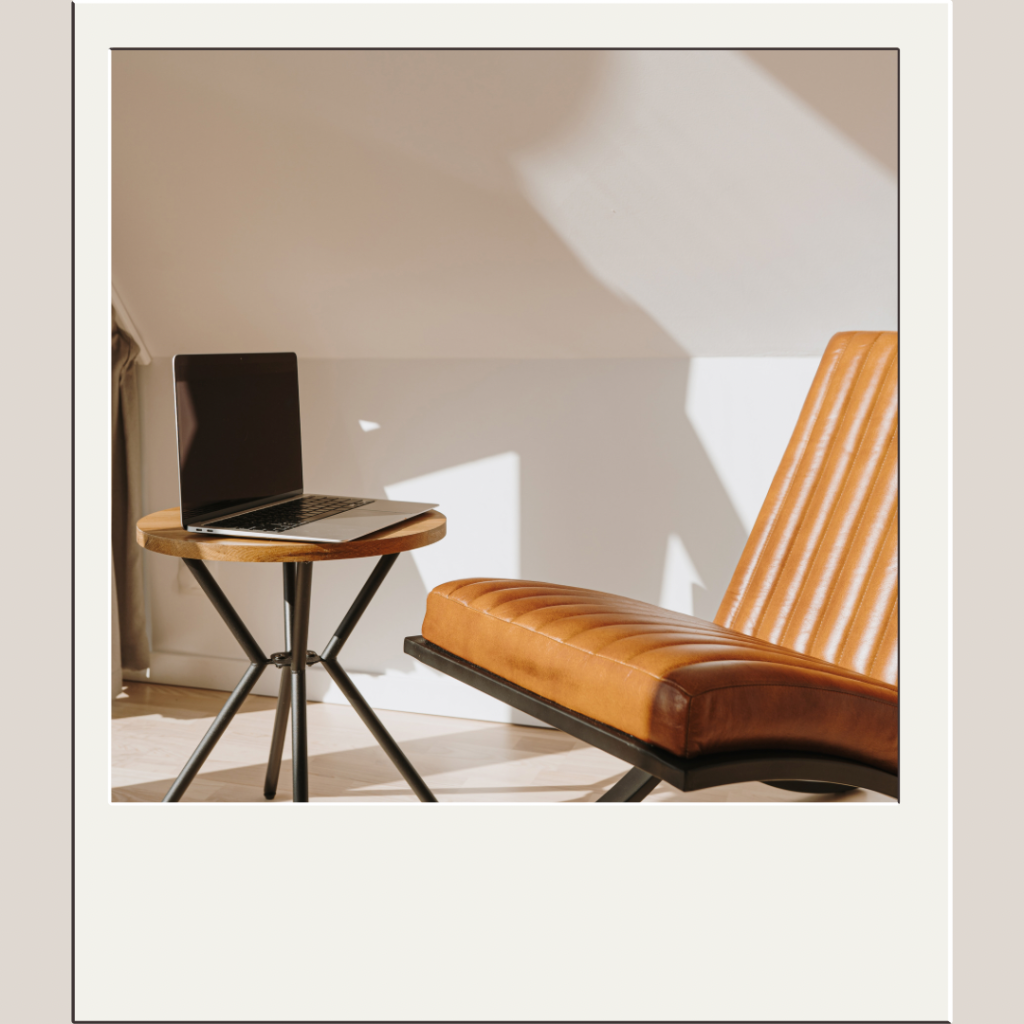 A laptop resting on a stool with a leather chair next to it - YOU Psychiatry Clinic