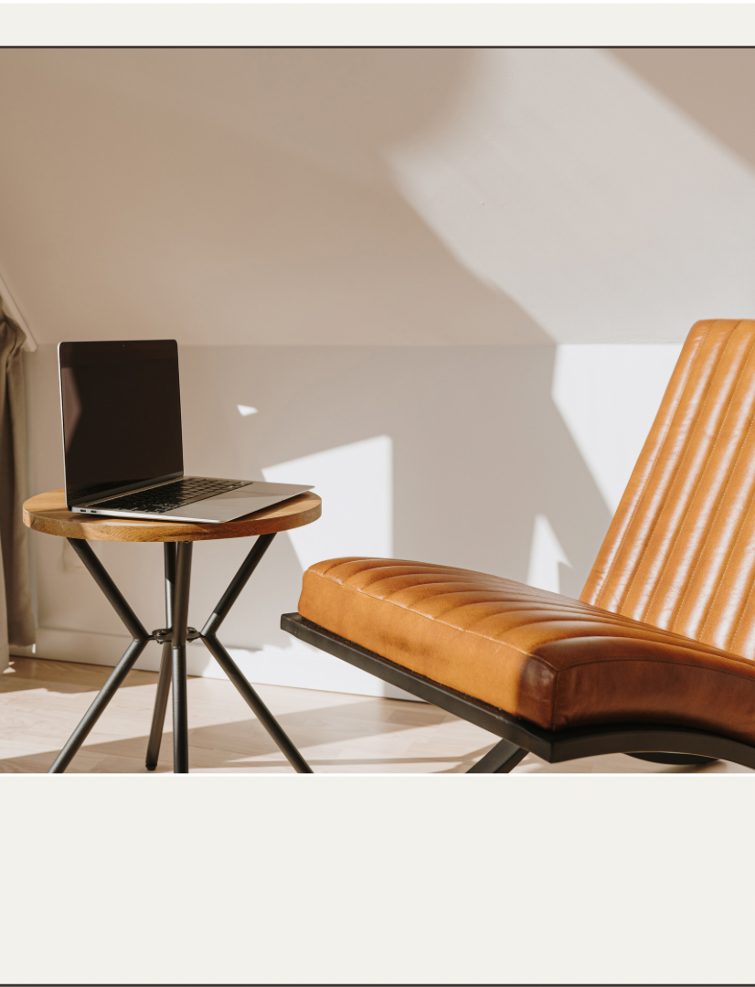 A laptop resting on a stool with a leather chair next to it - YOU Psychiatry Clinic